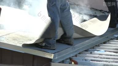 屋顶工人在平屋顶上使用热沥青安装最后一层膜